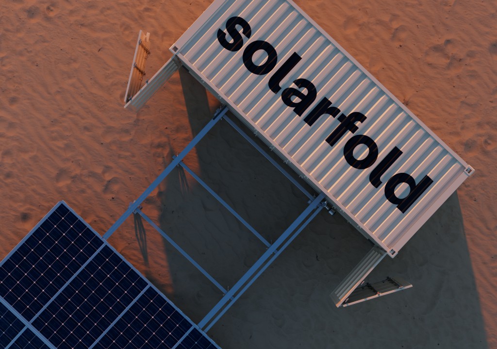 SolarFold deployable unit in desert sand: branded container with fold-out solar array and long golden-hour shadows